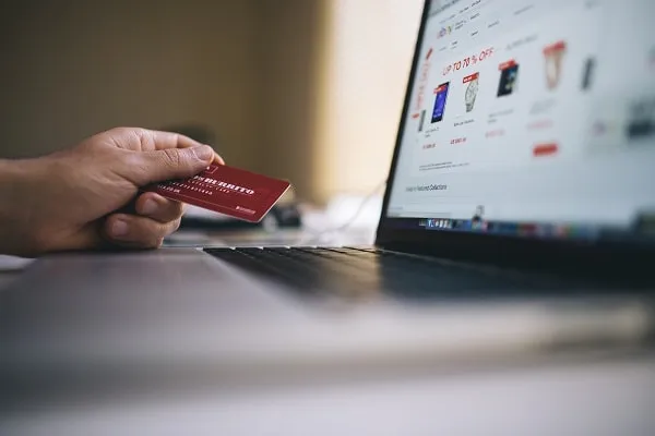 Person holding credit card buying something on laptop how to stop buying stuff you don't need