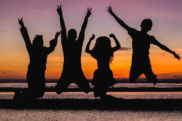 zonsondergang silhouet van vier mensen springen in de voorkant van een oceaan echte vriend