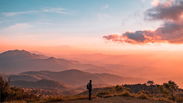 Man standing looking at mountain hill background with orange and blue sky 41 way to find peace of mind and inner calm