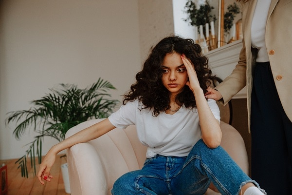 Girl in chair person putting hand on her shoulder to comfort how to be sensitive to other peoples feelings