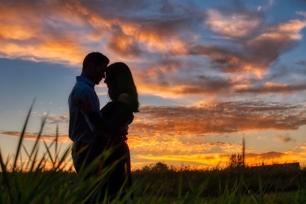 Couple standing holding each other in grassy land with sunset 15 relationship goals for couples to follow in 2021