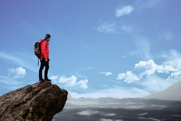 Man standing on mountaintop 15 steps to believe in yourself and have success